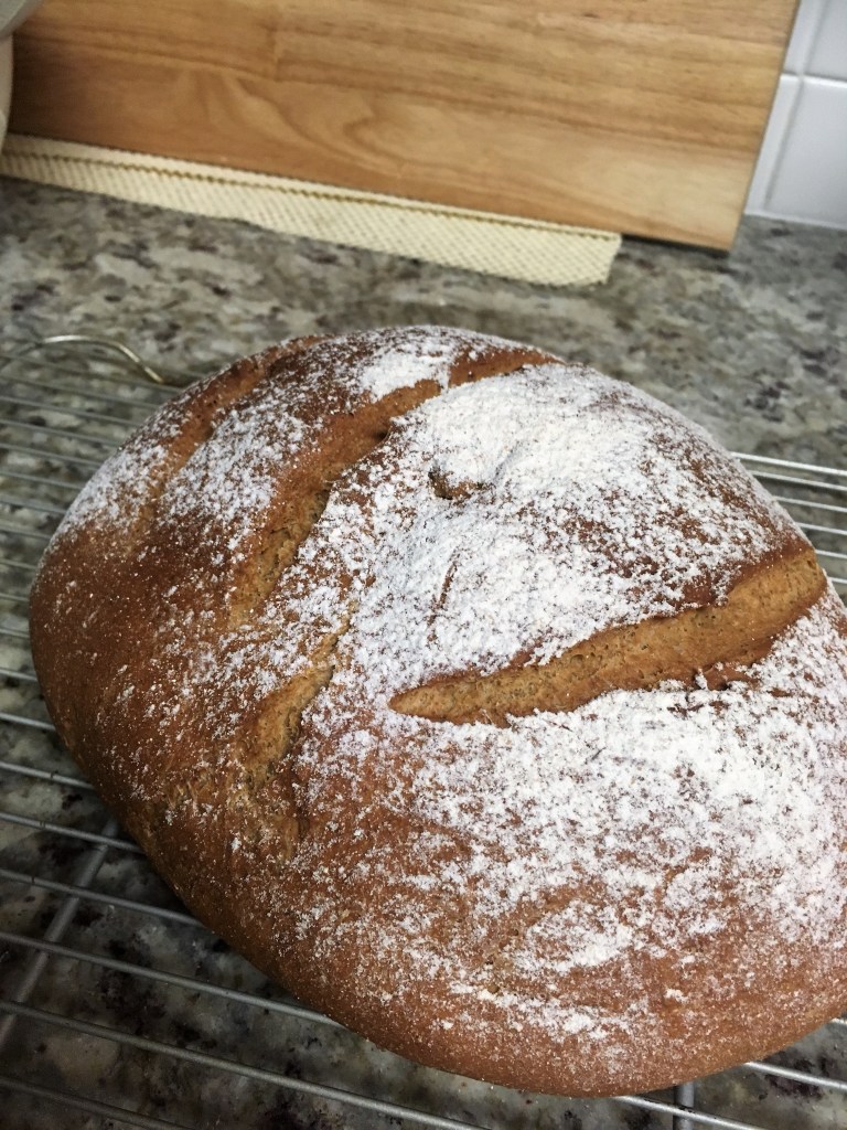 A dark spelt and rye loaf on a cooling rack