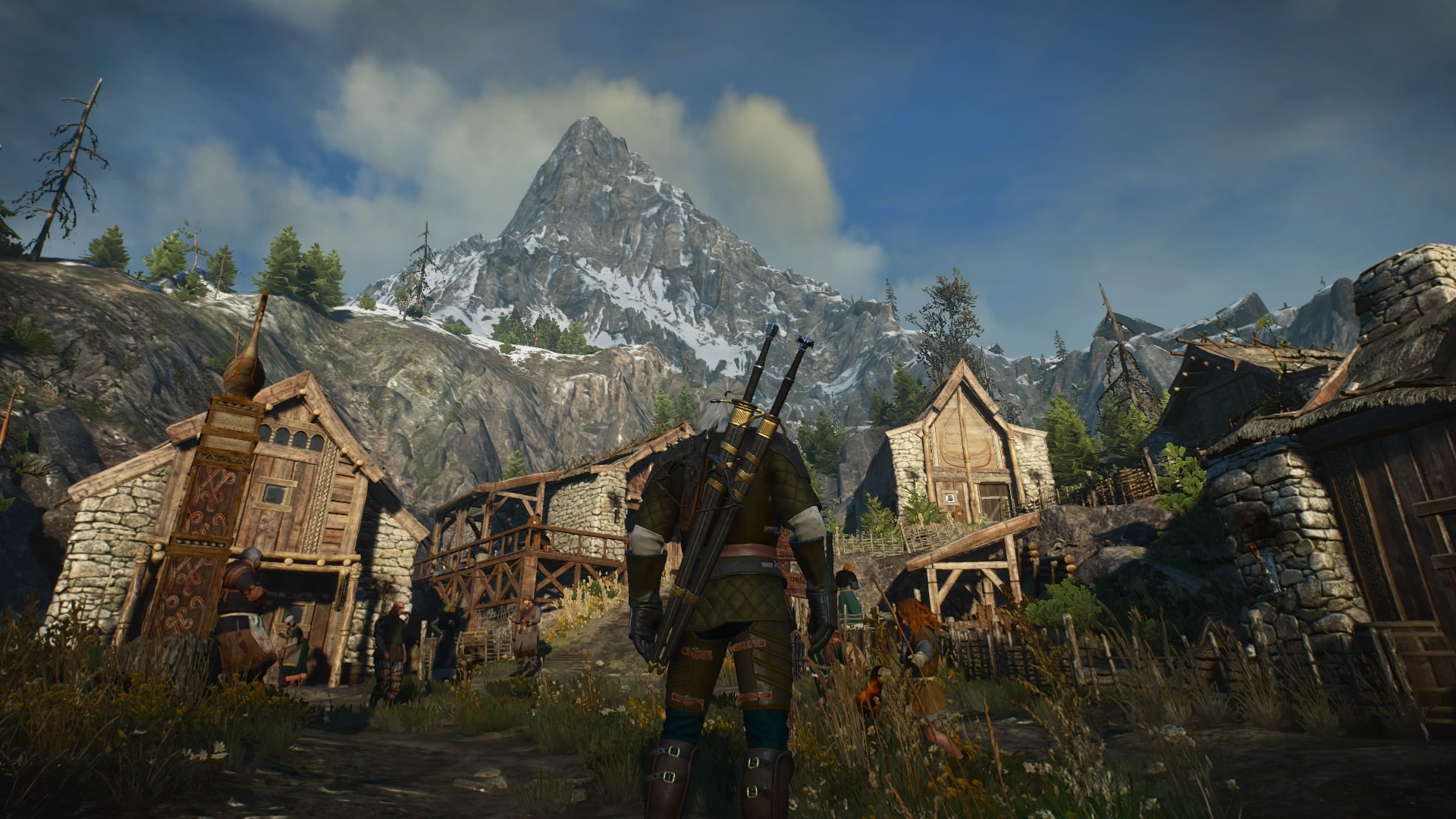 Geralt from The Witcher 3 looks at a town, mountains in the background
